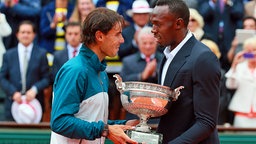 Usain Bolt (r.) überreicht French-Open-Gewinner Rafael Nadal den Pokal. © picture alliance / dpa Foto: Anton Denisov