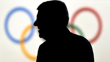 Die Silhouette von IOC-Präsident Thomas Bach vor den olympischen Ringen © picture alliance / dpa 