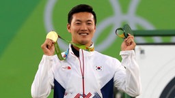 Der südkoreanische Bogenschütze Bonchan Ku mit seiner Olympischen Goldmedaille  © dpa Foto: Orestis Panagiotou