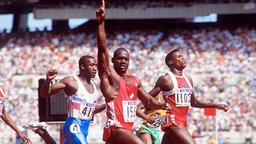 Ben Johnson (M.) jubelt bei den Olympischen Sommerspielen 1988 beim Zieleinlauf des 100-m-Finales. © picture-alliance / Sven Simon 