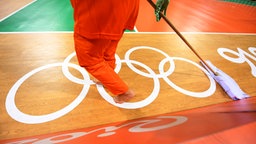 Ein Volunteer reinigt den Boden der Handball Arena. © dpa - Bildfunk Foto: Marijan Murat