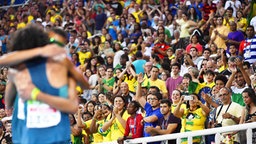 Die Fans auf der Tribüne jubeln, während sich die brasilianischen Läufer (l.) umarmen. © Imago/Kyodo News