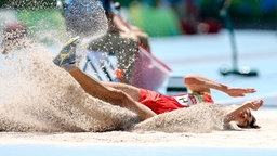 Der chinesische Leichtathlet Guanxu Shang springt in den Sand. © Imago/Beautiful Sports