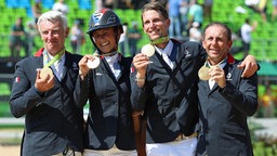 Roger Yves Bost, Penelope Leprevost, Kevin Staut, Philippe Rozier (v.l.n.r.) bejubeln ihre Goldmedaille im Mannschafts-Springreiten. © DPA Bildfunk Foto: Friso Gentsch