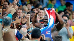 Der kubanische Ringer Mijain Lopez Nunez feiert seinen Sieg mit Fans. © dpa Foto: Sergei Ilnitsky