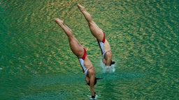 Die kanadischen Wasserspringerinnen Meaghan Benfeito und Roseline Filion springen ins grüne Wasser. © Imago/Xinhua