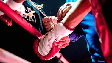 Einem Boxer wird der Handschuh zugebunden. © imago images/Reporters 