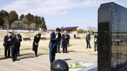Japans Premierminister Shinzo Abe verneigt sich in Namie in der Präfektur Fukushima vor einem Gedenkstein für die Opfer der Tsunami- und Nuklearkatastrophe von 2011. © imago images / Kyodo News 