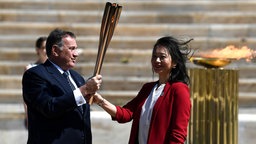 Spyros Kapralos übergibt die olympische Flamme an Naoko Imoto. © imago images/Xinhua 