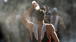 Der deutsche Triathlet Justus Nieschlag erfrischt sich in der Hitze des olympischen Triathlon-Rennens mit einer Flasche Wasser.