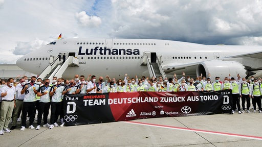 Das deutsche Team steht nach seiner Ankunft von den Olympischen Spielen in Tokio auf dem Flughafen vor einer Maschine der Lufthansa.