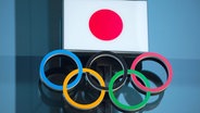 Symbolbild mit den Olympischen Ringen und der japanischen Flagge. © picture alliance/Morio Taga/Jiji Press Photo/dpa Foto: Morio Taga