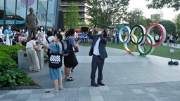 Menschen machen Selfies vor den Olympischen Ringen in Tokio. © NDR Foto: Bettina Lenner