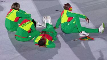 Bei der Eröffnungsfeier im Olympiastadion von Tokio sitzen vier Athleten aus Grenada auf dem Boden. © picture alliance/dpa/Sputnik | Vladimir Astapkovich Foto: Vladimir Astapkovich