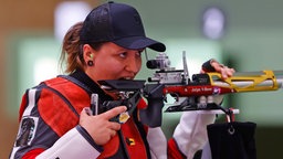 Die deutsche Sportschützin Jolyn Beer beißt nach dem letzten Schuss bei der Qualifikation der Frauen im Schießen mit dem Luftgewehr über 10 Meter in ihr Gewehr. © dpa-Bildfunk Foto: Oliver Weiken/dpa
