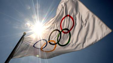 Eine Fahne mit den Olympischen Ringen, dahinter die hoch stehende Sonne © picture alliance/dpa/Sputnik | Alexey Filippov Foto: Alexey Filippov