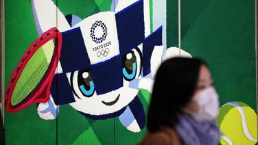 Frau mit Atemschutzmaske vor Werbeplakat für die Olympischen Sommerspiele in Tokio © picture alliance Foto: Mariko Ishizuka