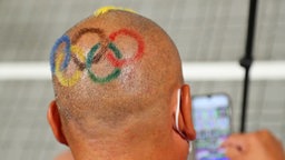 Ein Mann von der Delegation der Mongolei hat Olympische Ringe auf seinem Kopf gemalt. © dpa-Bildfunk Foto: Friso Gentsch/dpa