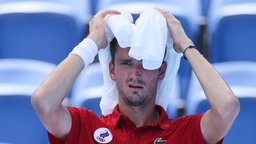 Der russische Tennisspieler Daniil Medvedev wischt sich den Schweiß vom Kopf. © imago images/Xinhua 