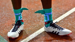 Der US-amerikanische Sprinter Noah Lyles mit grünen Socken, an denen Flügel befestigt sind. © IMAGO / Belga 