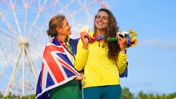 Die australische Kanutin Jessica Fox (r.) präsentiert ihre Goldmedaille im Canadier-Einer neben ihrer Mutter und Trainerin Myriam Fox-Jerusalmi © IMAGO / AAP