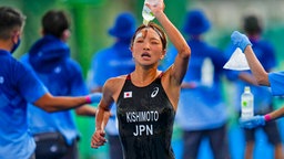 Die japanische Triathletin Niina Kishimoto kühlt sich bei der Mixed-Staffel ab. © picture alliance / ASSOCIATED PRESS | Francisco Seco
