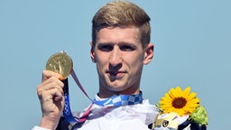 Der deutsche Schwimmer Florian Wellbrock präsentiert seine Goldmedaille im 10km Schwimmen. © dpd-bildfunk Foto: Oliver Weiken