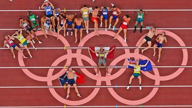 Die Athleten des Zehnkampfs posieren für ein Gruppen-Foto an den Olympischen Ringen. © dpa-Bildfunk Foto: Morry Gash/AP/dpa