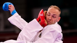 Der deutsche Karateka Noah Bitsch bekommt einen Fuß seines Gegners Yahiro Tsuneari aus Australien ins Gesicht. © dpa-Bildfunk Foto: Jan Woitas/dpa