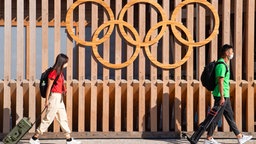 Eine Frau und ein Mann gehen durch das Olympische Dorf. © IMAGO / Bildbyran