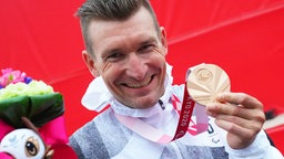 Der deutsche Para-Radsportler Matthias Schindler präsentiert seine Bronzemedaille. © dpa-Bildfunk Foto: Marcus Brandt/dpa