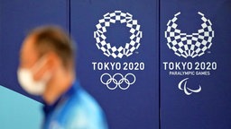 Ein Mann mit Maske läuft vor dem Logo der Paralympics in Tokio 2020. © IMAGO / Penta Press 