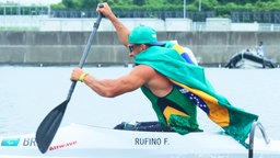 Der brasilianische Para-Kanute Fernando Rufino De Paulo fährt mit einer brasilianischen Flagge. © picture alliance / ASSOCIATED PRESS | Makoto Kondo